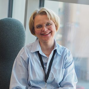 Kuvassa hymyilee Pirten ravitsemusterapeutti Katja, jolla on lyhyet vaaleat hiukset ja vaaleansininen paitapusero.