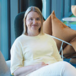 Kuvassa hymyilee Pirten työterveyspsykologi Mari Salo-Koskinen. Marilla on vaaleat olkapäille ulottuvat hiukset ja vaaleankeltainen pusero.
