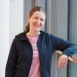 Kuvassa hymyilee Pirten fysioterapeutti Eeva, joka on erikoistunut muusikoiden fysioterapiaan. Eevalla on ruskeat hiukset ja yllään sininen hupputakki ja vaaleanpunainen paita.