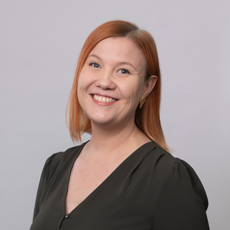 Kuvassa hymyilee Pirten vastaava työterveyshoitaja Elisa, jolla on punertavat olkapäille ulottuvat hiukset ja yllään tummanruskea pusero.