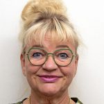 Kuvassa hymyilee Pirten työterveyshoitaja Milka-Riikka Rajala, jolla on vaaleat hiukset korkealla nutturalla ja vihreäsankaiset silmälasit.