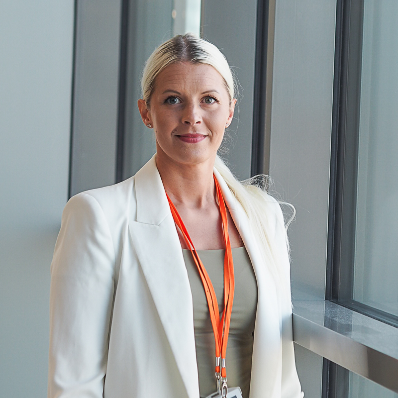 Kuvassa hymyilee Pirten asiakasneuvoja Janika, jolla on pitkät vaaleat hiukset ja yllään valkoinen bleiseri.